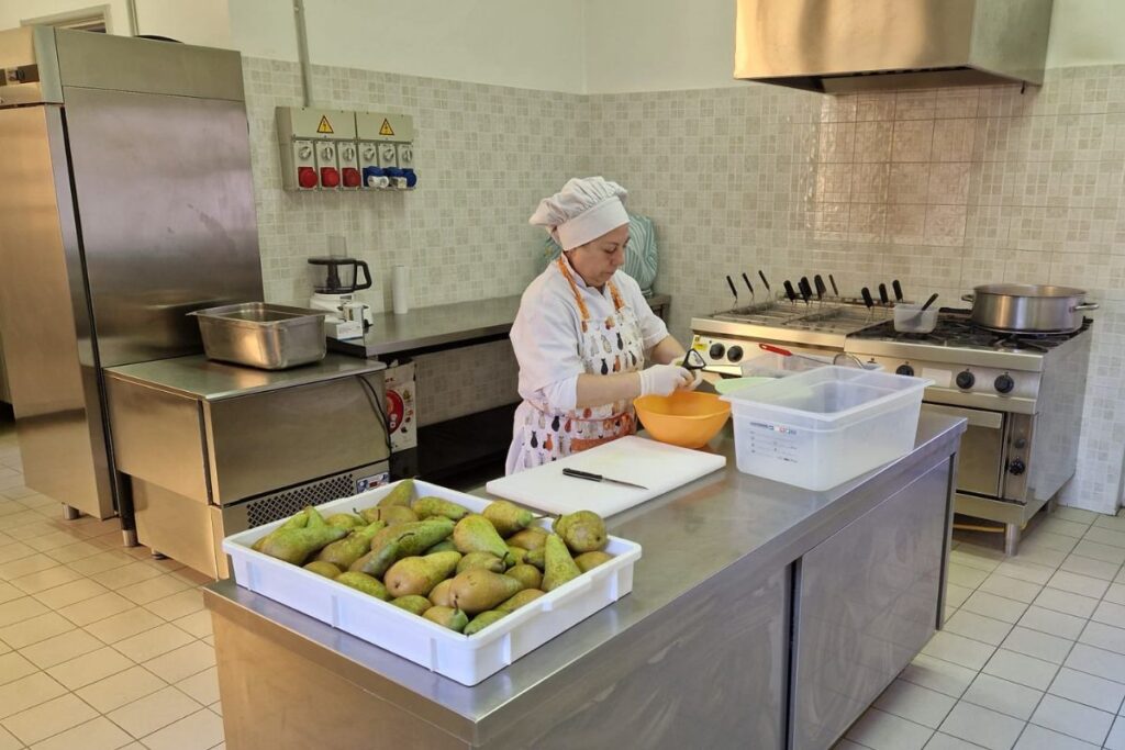 cuoca mentre prepara i piatti in una cucina scolastica