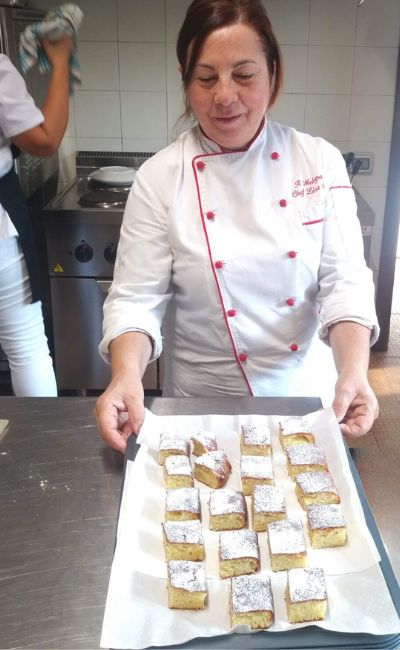 cuoca che mostra i dolci appena sfornati